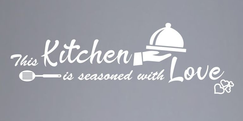 White kitchen wall decal with the phrase "This kitchen is seasoned with love," featuring a serving dish and spatula design.