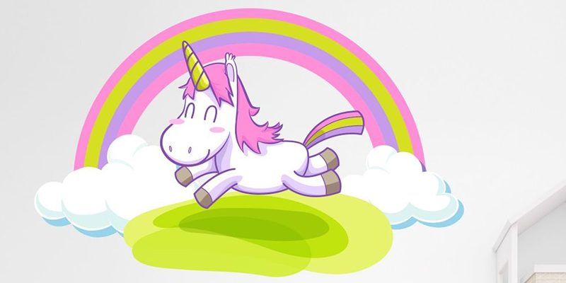 Rainbow sticker wall featuring a pink-maned unicorn flying over green hills with clouds and stars on a white wall.