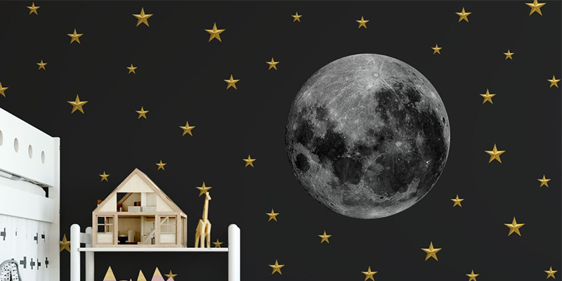 Wall décor featuring a realistic moon and golden stars on a dark background, creating a night-sky theme for a child's room.
