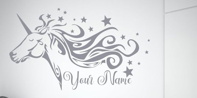 Wall decal featuring a flowing-maned unicorn with stars and space for a custom name, ideal for school decoration or personalization.