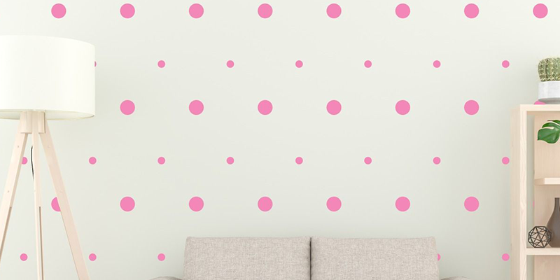 Wall decals featuring pink polka dots of various sizes arranged evenly on a white wall, adding a playful and modern touch.