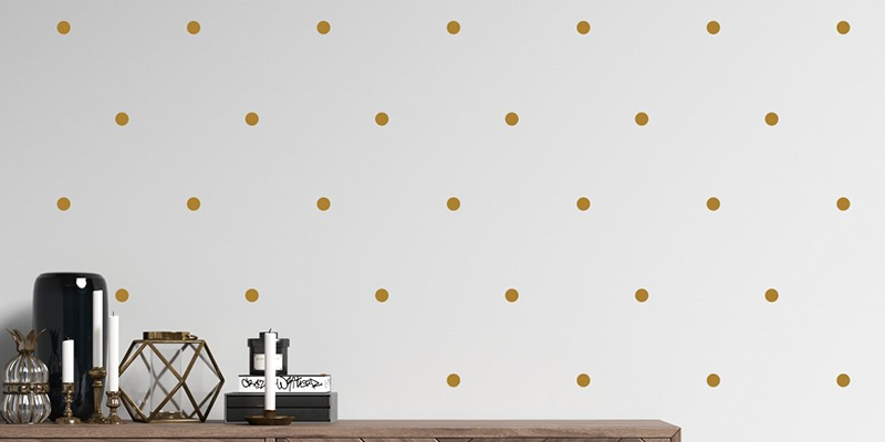Simple gold polka dot wall decals from Huetion evenly spaced on a white wall, ideal for adding a modern touch to any room.