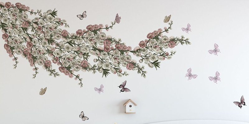 Wall decals featuring pink and white floral branches with fluttering butterflies, creating a soft, nature-inspired design.