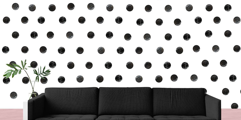 Black polka dot wall decals on a white wall, adding a modern touch ideal to decorate a small house with style.