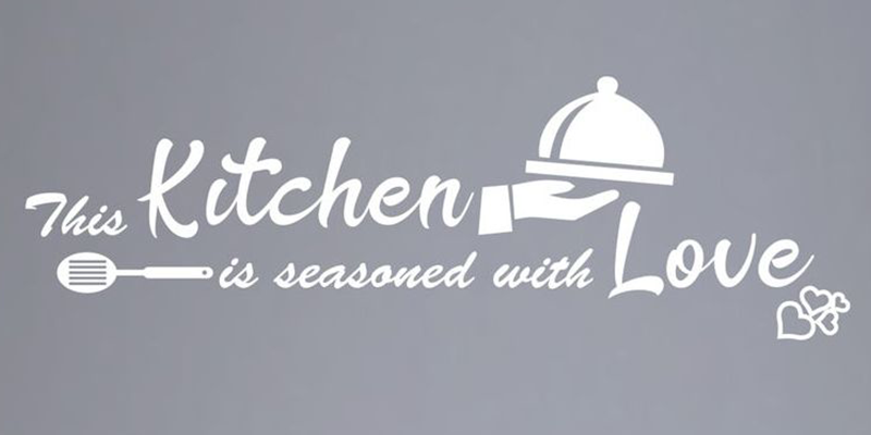 White kitchen wall decal with the phrase "This kitchen is seasoned with love," featuring a serving dish and spatula design.