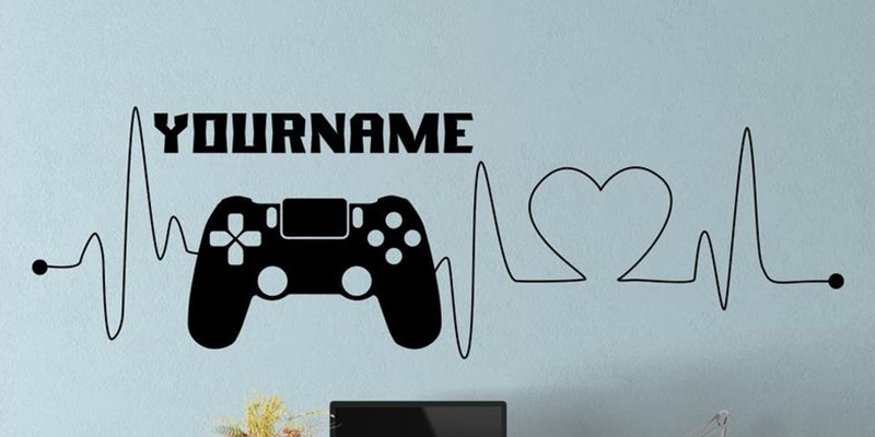 Black gamer wall decal for kids featuring a controller, heartbeat line, and customizable name. Great for gaming-themed rooms.