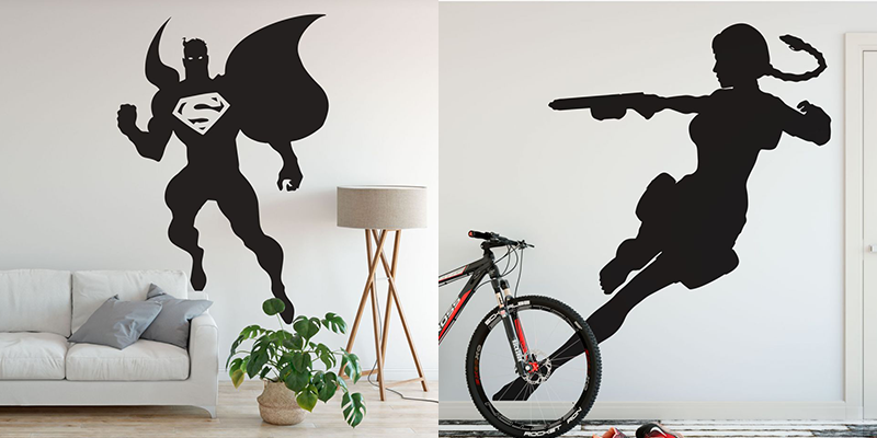 Black superhero wall decals featuring a flying hero with cape and a figure holding a weapon, decorating a modern room.