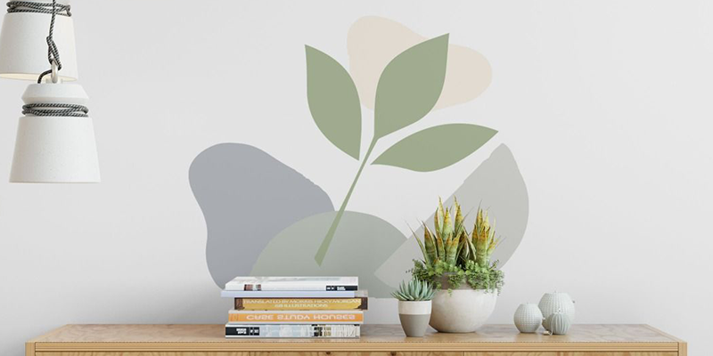 Boho-inspired wall stickers featuring a minimalist green leaf design with abstract shapes on a white wall above a shelf.