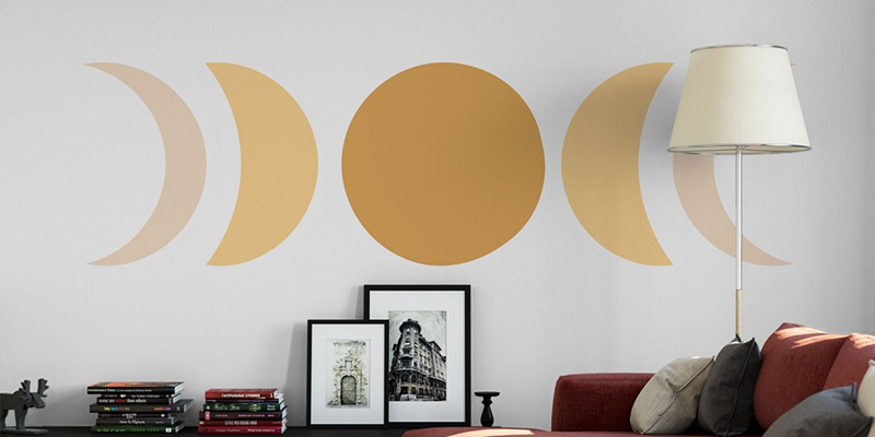 Boho-inspired wall stickers displaying a gold moon phase design on a white wall, adding a celestial touch to the room.