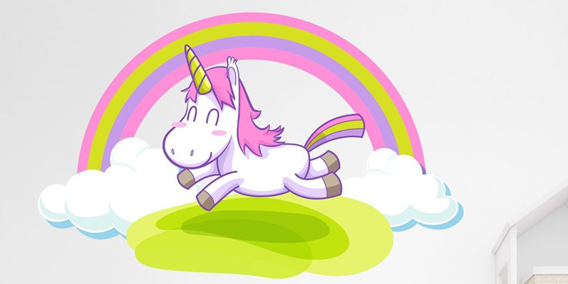 Rainbow sticker wall featuring a pink-maned unicorn flying over green hills with clouds and stars on a white wall.