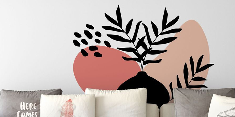 Boho wall decals featuring abstract black leaf patterns against peach and beige shapes, adding a modern touch to a neutral sofa.