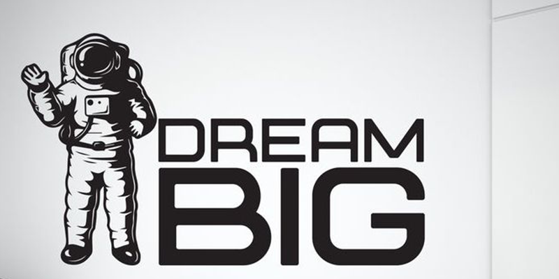 Space wall decal featuring an astronaut waving beside the bold text "Dream Big" in black.